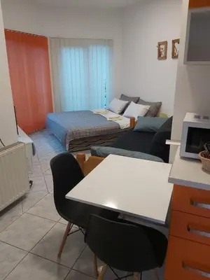 a room with two beds and a table and chairs at Apartmani Sladojević in Mrkonjić Grad