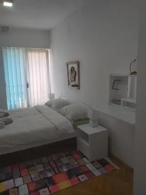 a bedroom with a bed and a table and a window at Apartmani Sladojević in Mrkonjić Grad