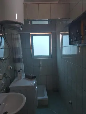 a bathroom with a sink and a toilet and a window at Apartmani Sladojević in Mrkonjić Grad