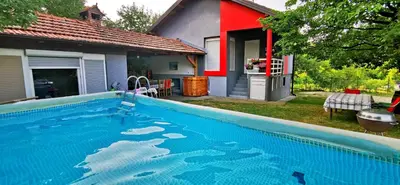 a large blue swimming pool in front of a house at Vikendica Delić Lukavac in Lukavac