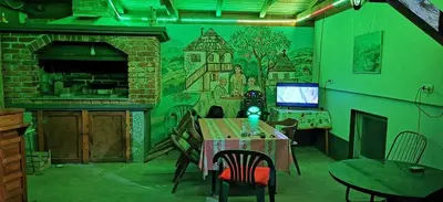 a dining room with a table and a green wall at Vikendica Delić Lukavac in Lukavac