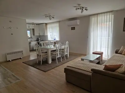 a living room with a table and chairs and a kitchen at Apartman Potok in Livno