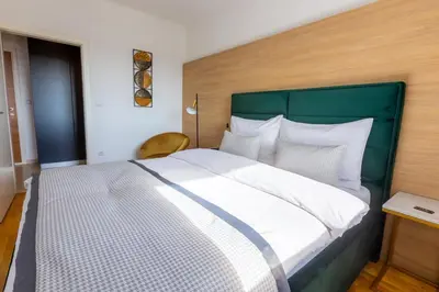 a bedroom with a large bed with a green headboard at Platinum_Luxury_Apartment in Teslić