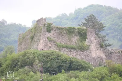an old stone building with plants on a mountain at Apartment Deluxe in Jajce