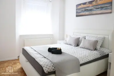 a white bedroom with a bed with a black bag on it at Apartment Deluxe in Jajce