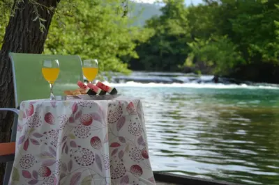 a table with two glasses of wine next to a river at Villa River and Sky in Bihać