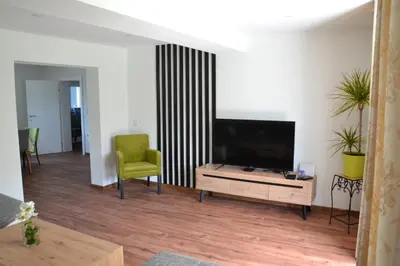 a living room with a flat screen tv and a green chair at Villa River and Sky in Bihać