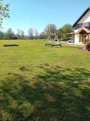 a large grassy field with a large shadow of a tree at Villa River and Sky in Bihać