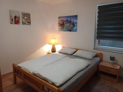 a bedroom with a bed with a lamp and a window at Rose Apartment in Jajce