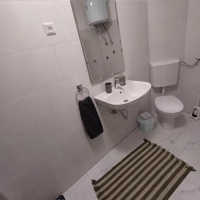a white bathroom with a sink and a toilet at Rose Apartment in Jajce