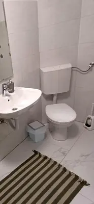 a white bathroom with a toilet and a sink at Rose Apartment in Jajce