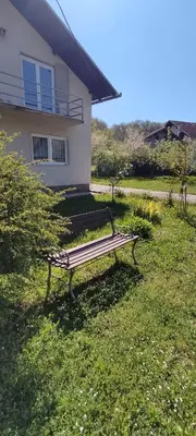 a park bench sitting in the grass in front of a house at Kuca za odmor Una-Mia in Kulen Vakuf