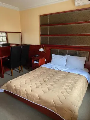 a bedroom with a large bed with a wooden headboard at Hotel Kamel in Banja Luka