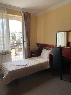 a hotel room with a bed and a desk and a window at Hotel Kamel in Banja Luka