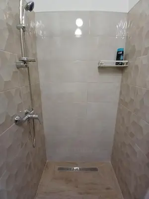 a shower in a bathroom with a tile wall at Apartment View in Jajce