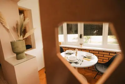 a table and chairs in a kitchen with windows at Apartman sunce Visoko in Visoko