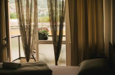 a bedroom with a window with a plant on a balcony at Apartman sunce Visoko in Visoko