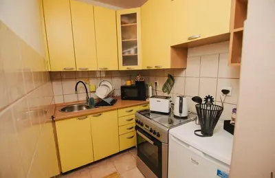 a small kitchen with yellow cabinets and a sink at Apartman sunce Visoko in Visoko