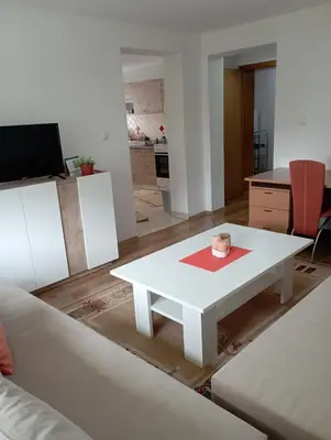 a living room with a white table and a kitchen at Apartman U&O Bihać in Bihać