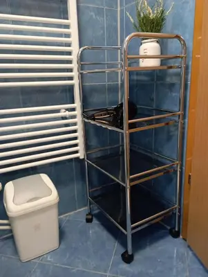 a blue tiled bathroom with a toilet and a shelf at Apartman U&O Bihać in Bihać