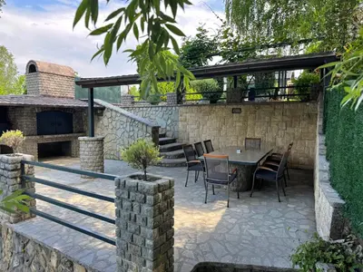 a patio with a table and chairs and a stone wall at Sunrise Guest House in Bihać