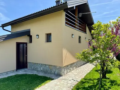 a house with a black door and a yard at Sunrise Guest House in Bihać