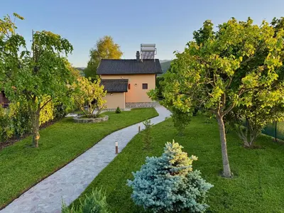 a garden with a house and a walkway at Sunrise Guest House in Bihać