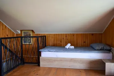 a bed in a room with wooden walls and wooden floors at Sunrise Guest House in Bihać