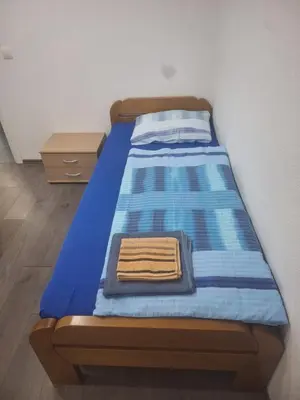 a bed with a blue comforter and towels on it at Apartman Knežević in Donja Varoš