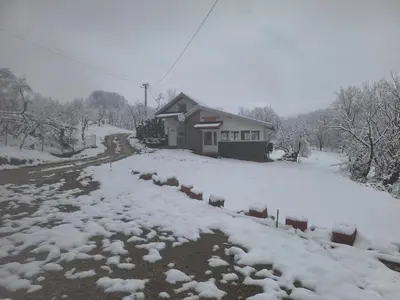 a snow covered yard with a house in the background at Vikendica Avram-Plane in Plane