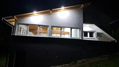 a house with windows on the side of it at night at Vikendica Avram-Plane in Plane