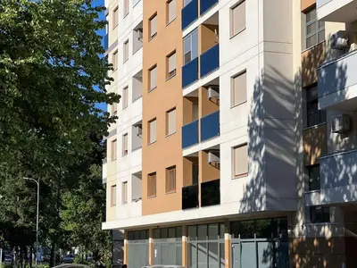 a tallartment building with a parking lot in front of it at STENI Apartman in Doboj