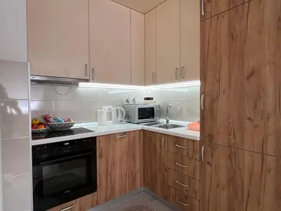 a kitchen with wooden cabinets and a microwave at STENI Apartman in Doboj
