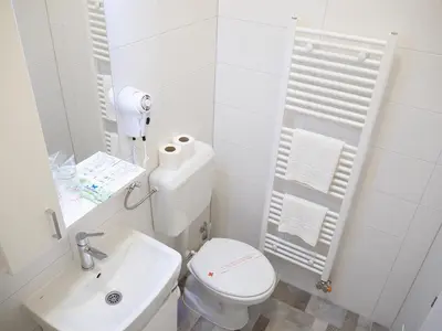 a white bathroom with a toilet and a sink at Motel Rezime in Zenica