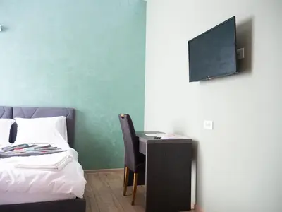 a bedroom with a bed and a desk with a television at Motel Rezime in Zenica