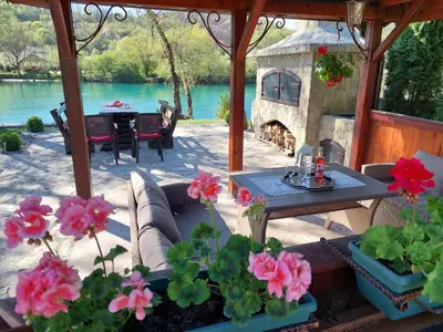a patio with a table and a stone fireplace at Bosanska kuća Emina in Bihać