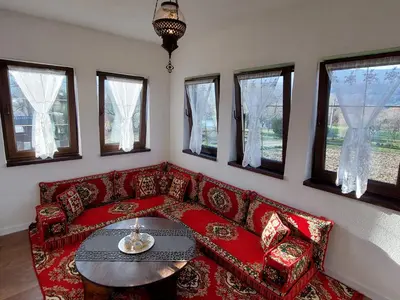a living room with a red couch and a table at Bosanska kuća Emina in Bihać