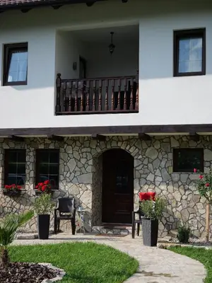 a house with a balcony and a door and flowers at Bosanska kuća Emina in Bihać