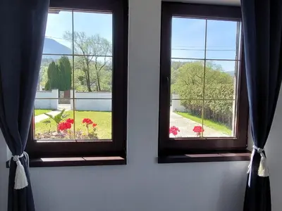 two windows in a room with red flowers in a yard at Bosanska kuća Emina in Bihać