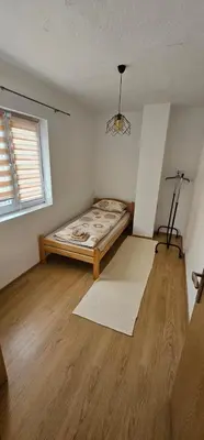 a bedroom with a bed in the corner of a room at Apartman Naza in Kulen Vakuf