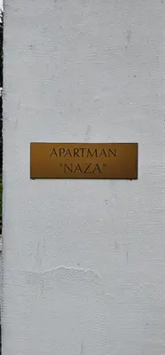 a sign on the side of a white wall at Apartman Naza in Kulen Vakuf