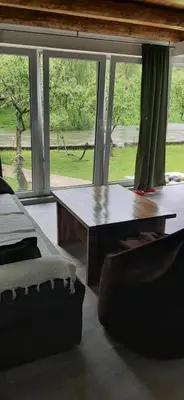a living room with a table and a large window at Apartman Vrbas in Jajce