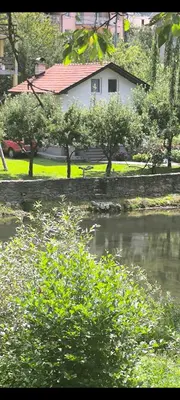 a house and a pond in front of a house at Apartman Vrbas in Jajce