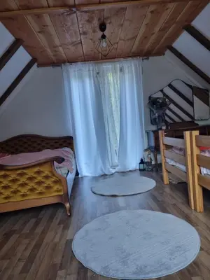 a bedroom with a bed and two rugs on the floor at Vikendica za odmor in Busovača