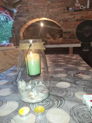 a candle in a glass vase on a table with a fireplace at Vikendica za odmor in Busovača