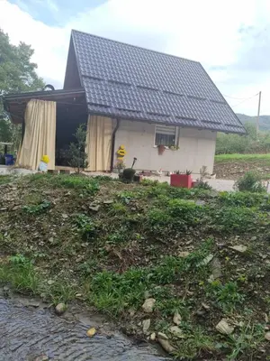 a house with a black roof on top of a yard at Vikendica za odmor in Busovača