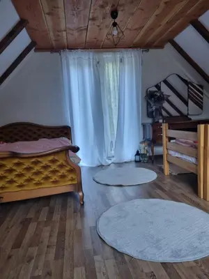 a bedroom with a bed and two rugs on the floor at Vikendica za odmor in Busovača