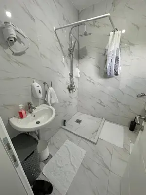 a white bathroom with a sink and a shower at CIOM Apartment in Matuzići
