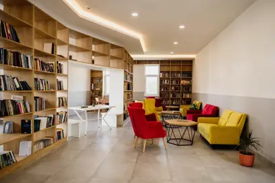 a library with yellow and red chairs and bookshelves at CIOM Apartment in Matuzići
