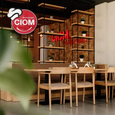 a restaurant with wooden tables and chairs and a sign at CIOM Apartment in Matuzići